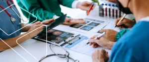 Equipe de profissionais da saúde analisando documentos e registros para controle documental e conformidade com a ISO 9001.